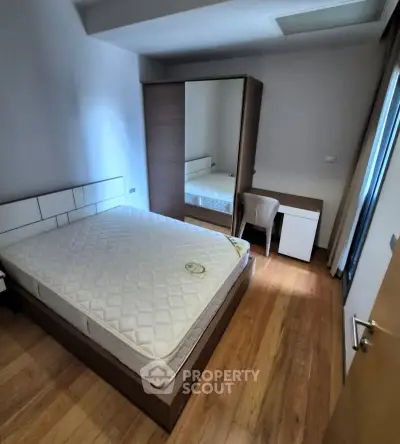 Cozy bedroom with wooden flooring, modern wardrobe, and comfortable bed.