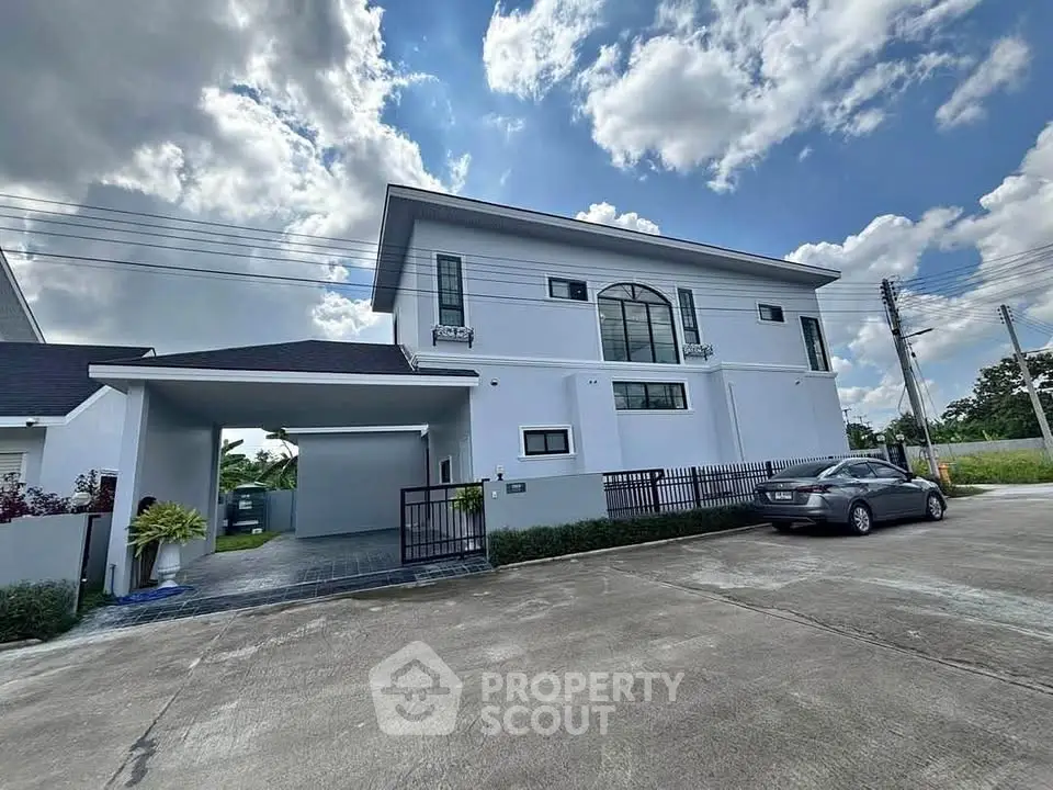 Stunning modern two-story house with spacious driveway and lush surroundings under a bright blue sky.