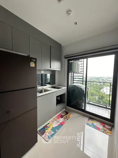 Modern kitchen with sleek cabinetry and balcony view, featuring a spacious fridge and stylish floor mats.