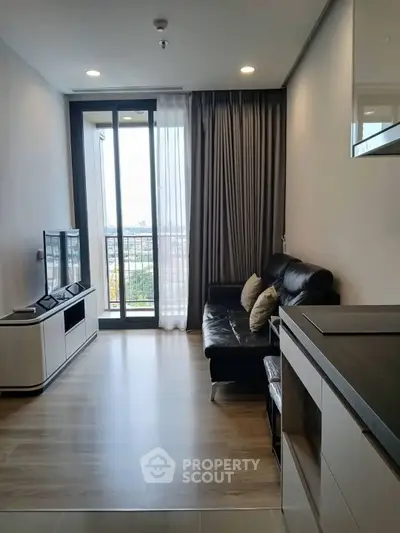 Modern living room with sleek furniture and large window offering city views.