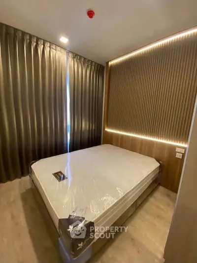 Modern bedroom with elegant lighting and floor-to-ceiling curtains, featuring a cozy bed setup.