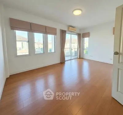 Spacious empty room with large windows and wooden flooring, perfect for customization.