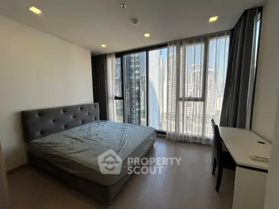 Modern bedroom with large windows offering stunning city views in a high-rise apartment.