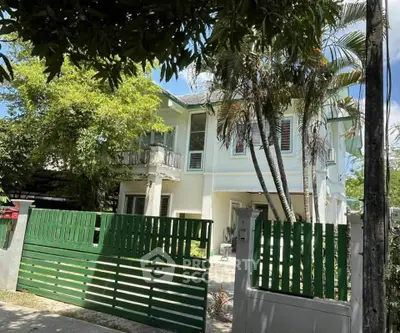 Charming two-story house with lush greenery and secure gated entrance, perfect for family living.