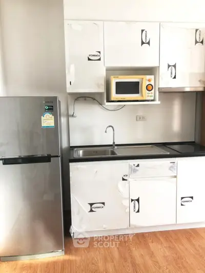 Modern kitchen with stainless steel fridge and microwave in sleek apartment