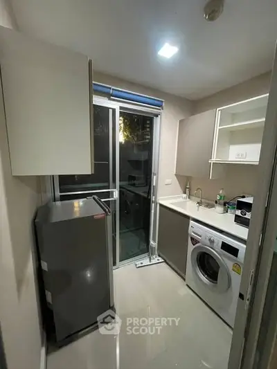 Modern kitchen with washing machine and fridge in sleek apartment