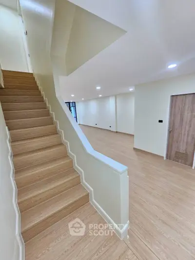 Spacious modern interior with wooden staircase and open living area, perfect for contemporary living.