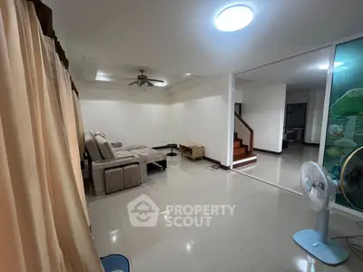 Spacious living room with modern sofa and ceiling fan, ideal for family gatherings.
