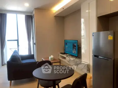 Modern living room with sleek furniture and natural light, featuring a TV and stylish decor.