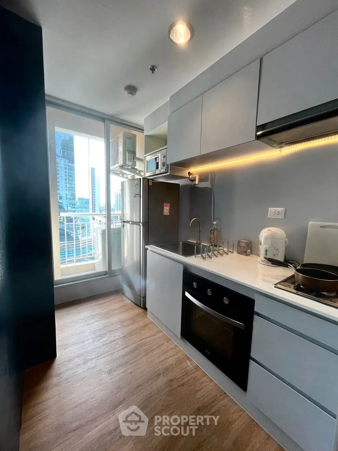 Modern kitchen with sleek cabinetry, built-in oven, and city view from window.