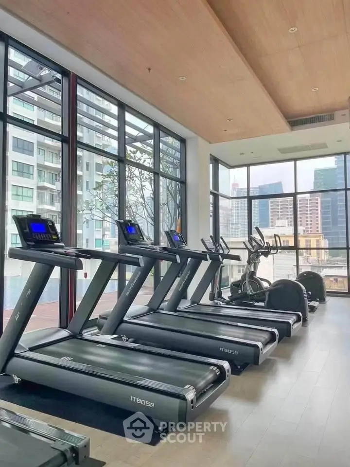 Modern gym with city view and state-of-the-art equipment in luxury residential building.