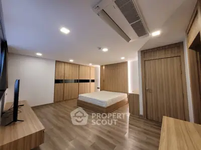 Spacious modern bedroom with wooden flooring and built-in wardrobe