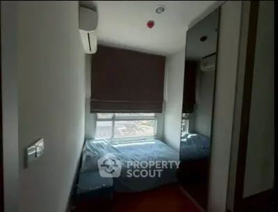 Cozy bedroom with air conditioning and large window offering natural light.