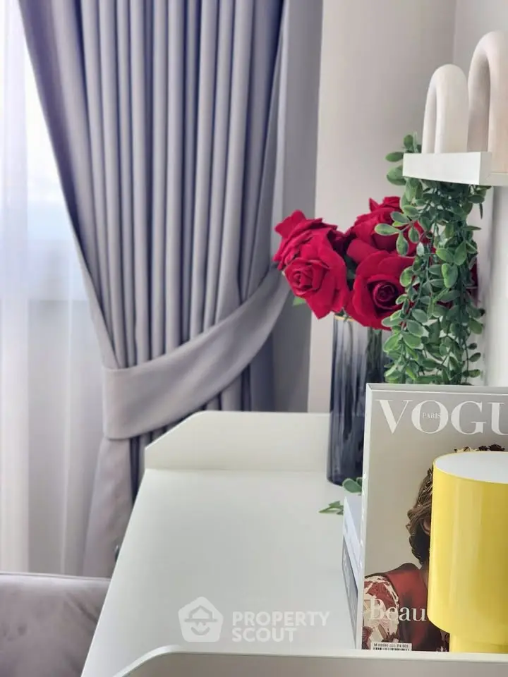 Elegant interior with stylish decor, featuring red roses and a magazine on a chic white table.
