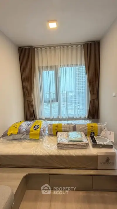 Cozy bedroom with modern decor and city view, featuring a comfortable bed and stylish curtains.