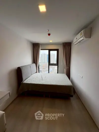 Modern bedroom with city view, featuring a comfortable bed and air conditioning.