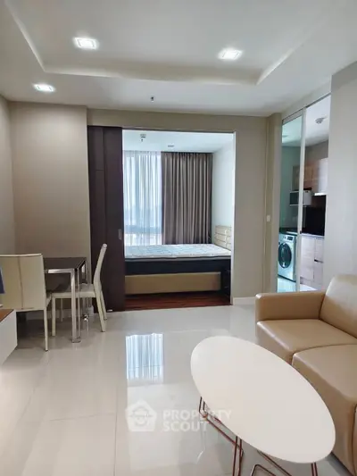 Modern studio apartment with open layout, featuring a cozy living area and a compact kitchen with washing machine.