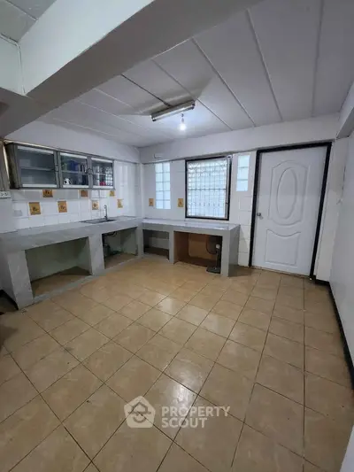 Spacious kitchen with tiled floor and ample counter space in a modern home.