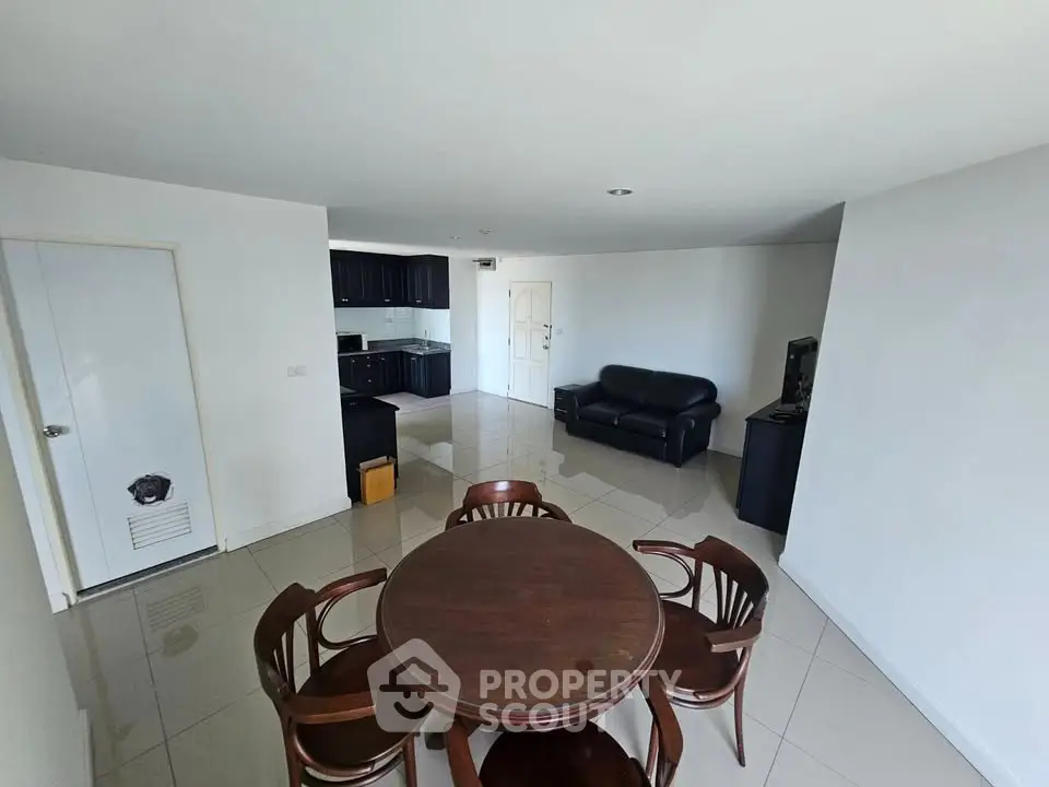 Spacious living room with dining area and modern kitchen in open layout apartment.