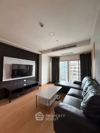 Spacious modern living room with sleek furniture and large window view.