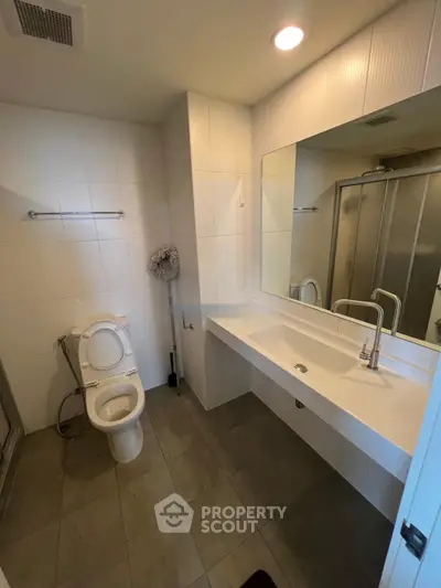 Modern bathroom with sleek fixtures and large mirror in a contemporary apartment.