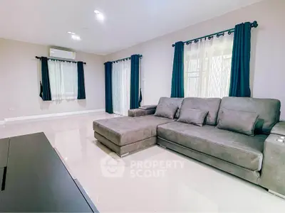 Spacious living room with modern gray sectional sofa and elegant curtains