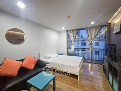 Modern studio apartment with stylish decor and city view balcony, featuring cozy living area and comfortable bed.