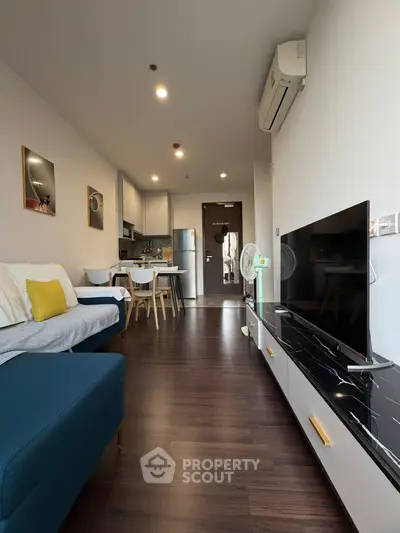 Modern living room with sleek furniture and open kitchen layout, featuring a cozy ambiance.