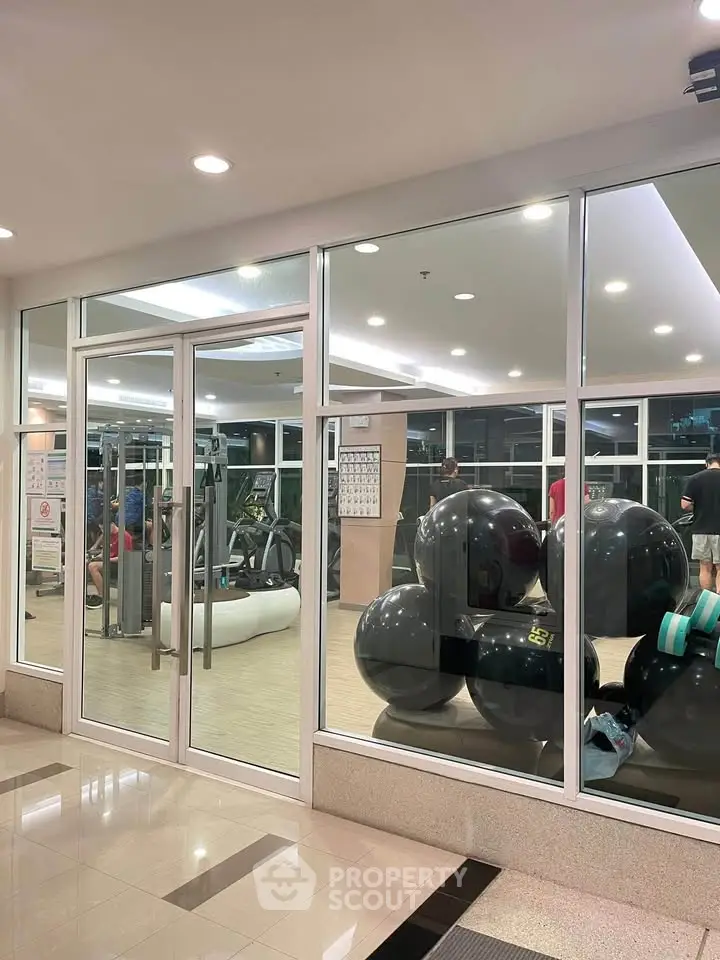 Modern gym with large windows and fitness equipment in a luxury residential building.