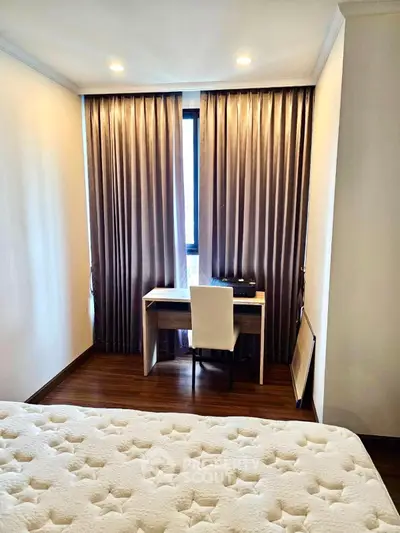 Cozy bedroom with study nook, featuring elegant curtains and a comfortable bed.