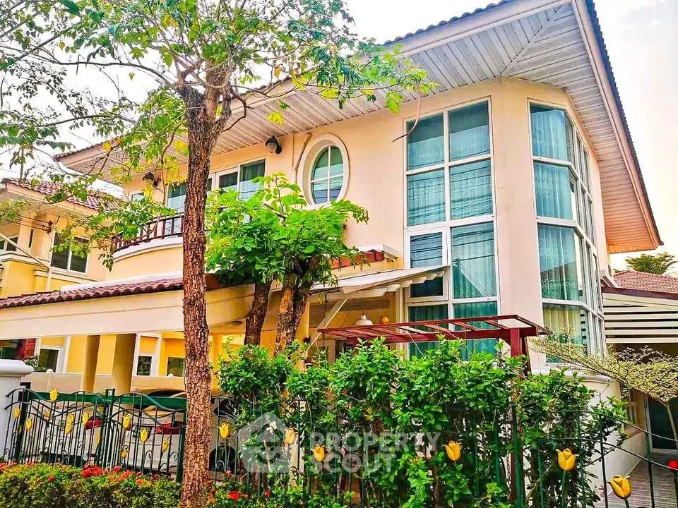 Stunning two-story house with large windows and lush garden, perfect for family living.