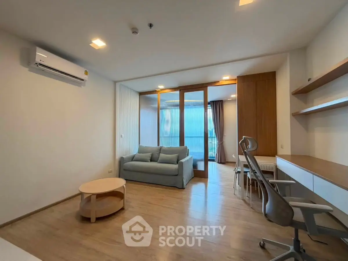 Modern living room with wooden flooring, stylish furniture, and large windows for natural light.
