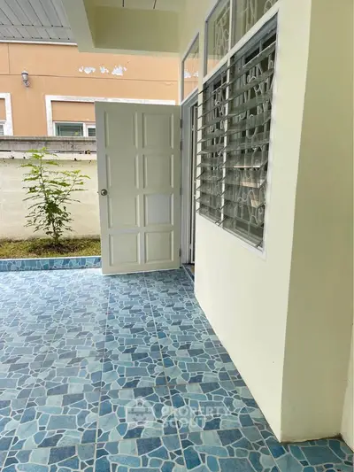 Charming exterior view of a home with blue tiled patio and open door inviting natural light.