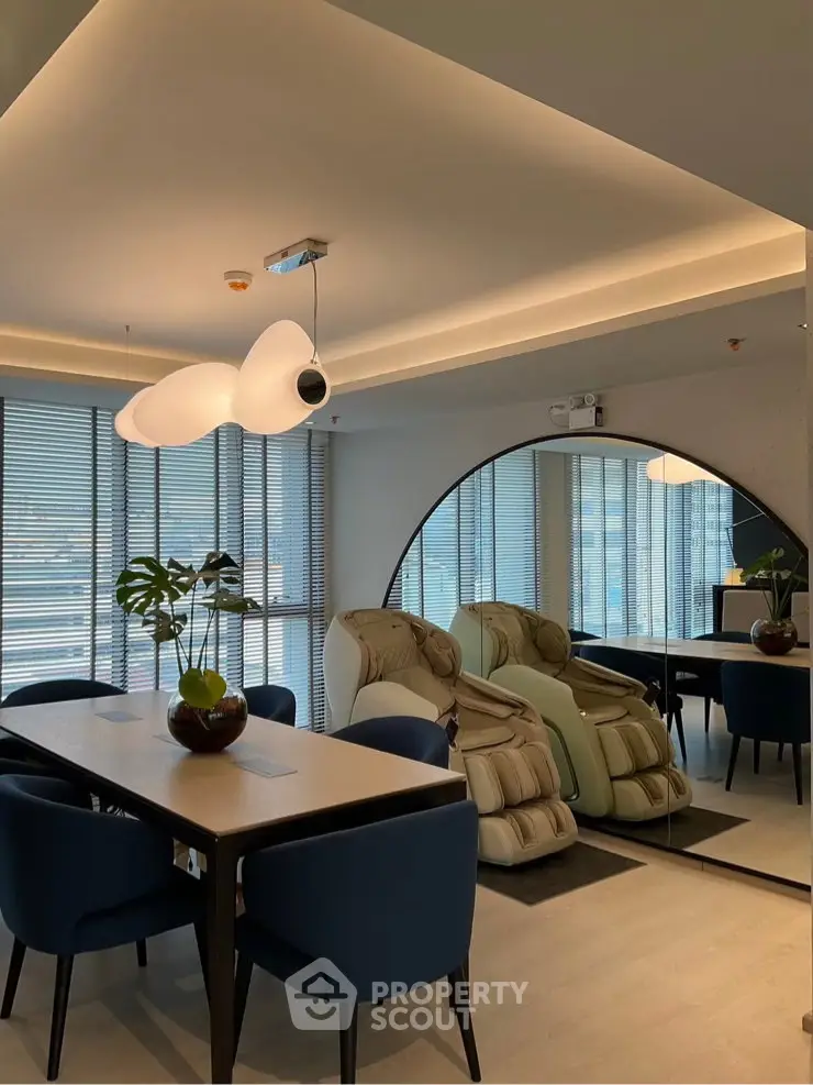 Modern dining area with stylish lighting and massage chairs, featuring large mirror and elegant decor.