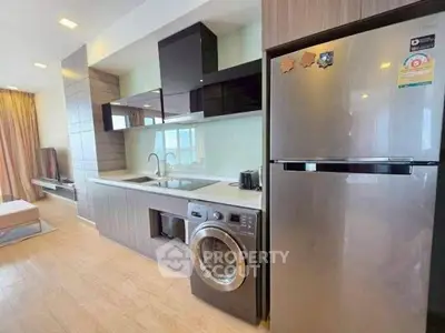 Modern kitchen with sleek appliances and integrated washing machine in stylish apartment.