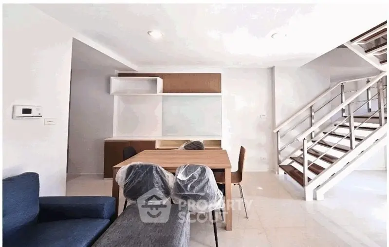 Modern living room with stylish staircase and dining area in a contemporary home.