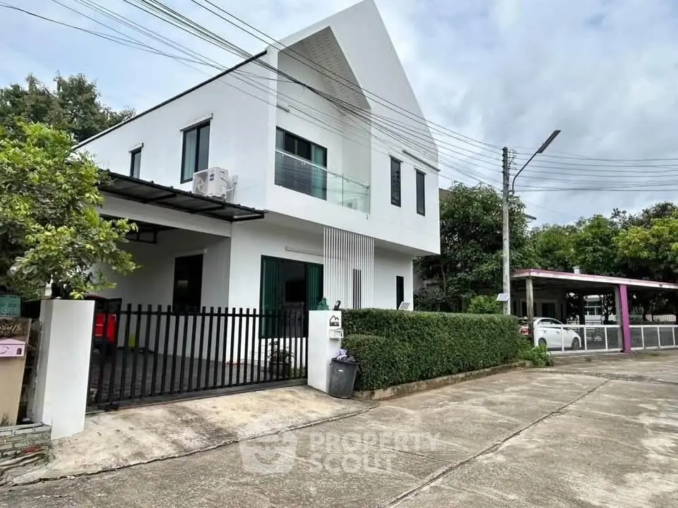 Modern two-story house with sleek design and gated entrance in a suburban neighborhood.