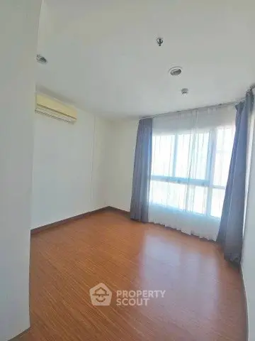 Spacious empty room with wooden flooring and large window, perfect for customization.