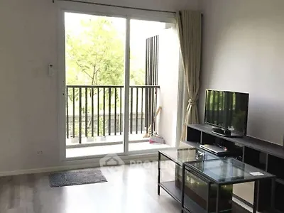 Bright living room with glass doors leading to a balcony, featuring modern TV stand and glass coffee table.