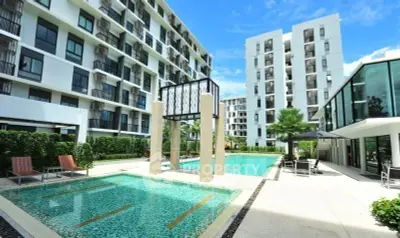 Modern apartment complex with luxurious swimming pool and sun loungers, perfect for relaxation.