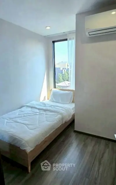 Cozy minimalist bedroom with large window and air conditioning unit.