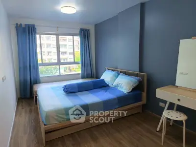 Bright bedroom with blue accents and large window in modern apartment.