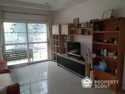 Spacious living room with large window and modern shelving unit.