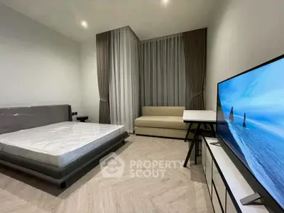 Modern bedroom with sleek design, featuring a large bed, sofa, and flat-screen TV.