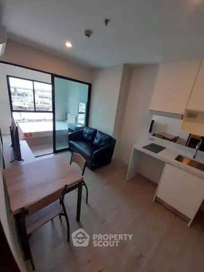 Modern open-plan living room with kitchen and balcony view in urban apartment