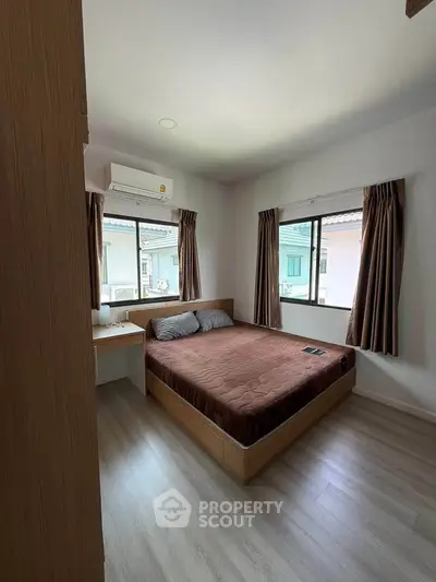 Cozy bedroom with large windows and modern furnishings in a bright home.