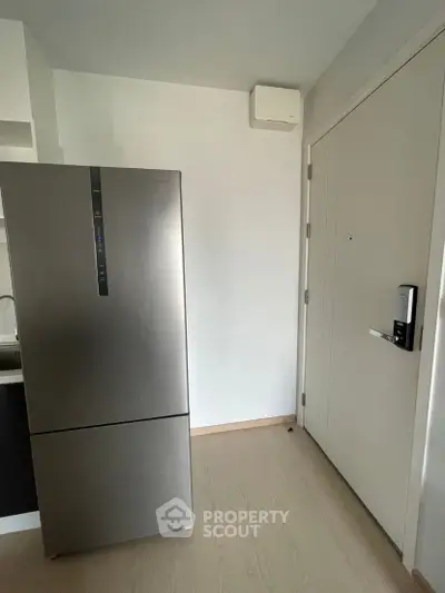 Modern apartment entrance with sleek refrigerator and secure door lock system.