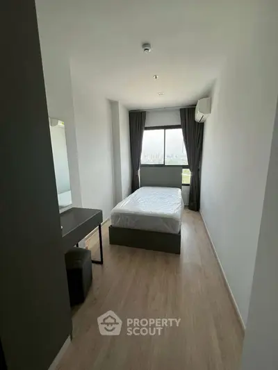 Modern minimalist bedroom with natural light and sleek furnishings in a high-rise apartment.
