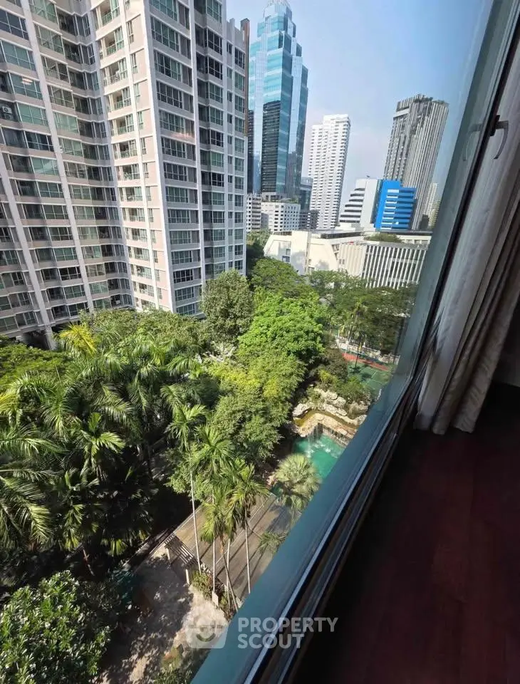 Stunning cityscape view from high-rise apartment window overlooking lush greenery and modern skyscrapers.