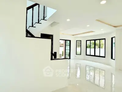 Spacious modern living room with large windows and elegant staircase